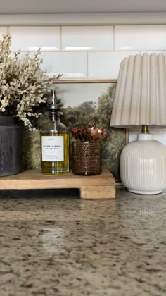 a bottle of olive oil sitting on top of a counter next to a lamp