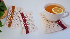 a cup of tea sitting next to a pair of knitted mitts and a pot holder