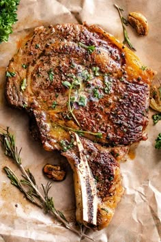 a piece of meat sitting on top of a table next to some vegetables and herbs