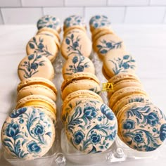 there are many blue and white decorated cookies in the plastic container on the counter top