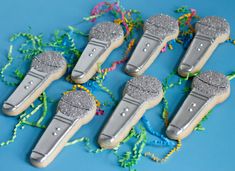 five silver guitar pickers sitting on top of a blue table next to streamers