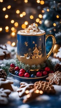 a blue and gold coffee cup with christmas decorations on it, surrounded by gingerbreads