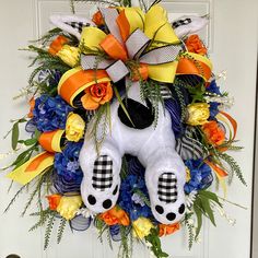 a wreath that has been decorated to look like a dog with yellow, orange and blue flowers