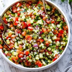 a white bowl filled with cucumber and red onion salad on top of a marble counter