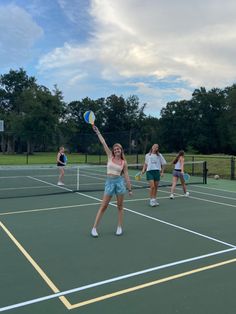 a group of people standing on top of a tennis court holding racquets