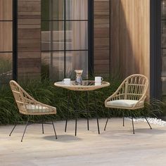 two wicker chairs sitting next to each other near a table