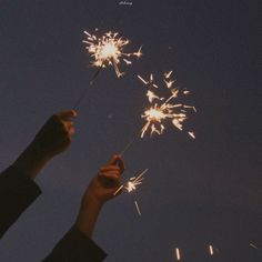 a person holding a sparkler in the air with their hand up to it's side