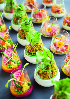 a table topped with lots of different types of small containers filled with veggies