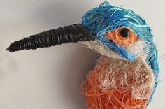 an orange and blue bird with a black beak on it's head sitting on a white wall