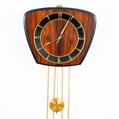 a wooden clock with gold chains hanging from it's sides