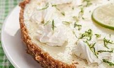 a white plate topped with a cheesecake covered in sour cream and garnished with lime