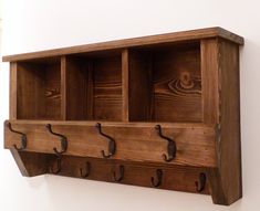 a wooden shelf with four hooks on it