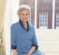 an older woman sitting in front of a window with her hands on her hips and smiling