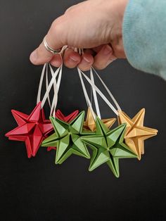 three origami stars being held by a person's hand on a black background