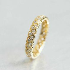 a yellow gold ring with small diamonds on the inside and outside, sitting on a white surface