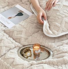 a woman is cleaning her bed with a towel and two candles in front of it