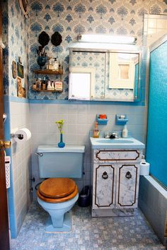 a blue and white bathroom with a toilet, sink, mirror and cabinet in it