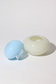 two white and light blue vases sitting next to each other on a white surface