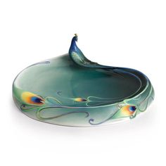 a glass bowl with a peacock design on the bottom and an oval shaped basin below it