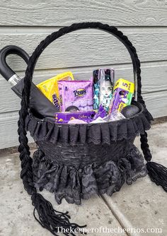 a black basket filled with candy and other items sitting on top of a cement floor