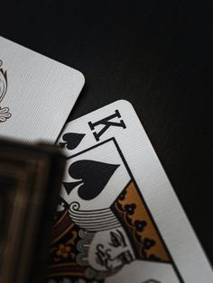 two playing cards sitting next to each other on top of a black table with a wooden frame