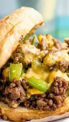 a sloppy joe sandwich on a bun with cheese and green peppers in the middle, ready to be eaten