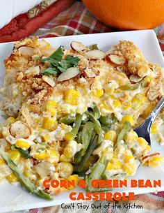 corn and green bean casserole on a white plate with a fork next to an orange