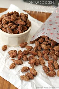 a white bowl filled with cinnamon sugar candies next to a paper bag on top of a wooden table