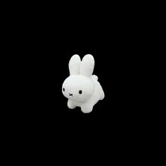 a white stuffed animal in the dark with its head turned to look like a bunny