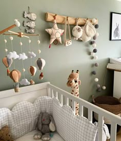 a baby crib with stuffed animals hanging from it's hooks and decorations on the wall