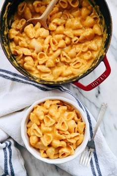 a bowl of macaroni and cheese with a wooden spoon next to it on a towel