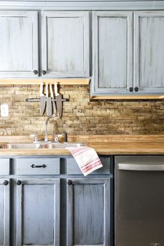 a kitchen with gray cabinets and wooden counter tops, an old fashioned dishwasher