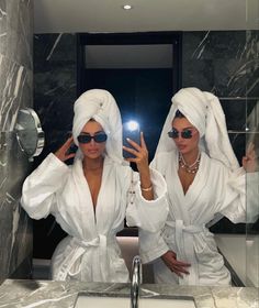 two women in white robes are taking a selfie