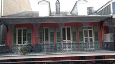 a red building with white balconies and green shutters on the second story