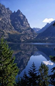 the mountains are reflected in the still water of this mountain lake that is surrounded by pine trees