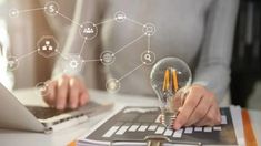 a person working on a laptop while holding a light bulb