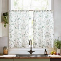 a kitchen sink under a window covered in floral curtain valances and potted plants