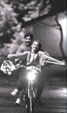 a man and woman riding on the back of a motorcycle