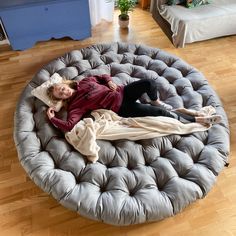 a woman laying on top of a round bed in the middle of a living room