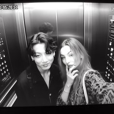 two women are standing in an elevator talking on the phone