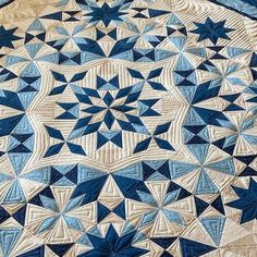 a large blue and white quilt on top of a wooden tablecloth covered in an intricate design