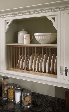 a kitchen with white cabinets and dishes on the shelf above the stove top is filled with food