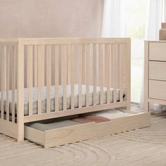 a baby crib with a drawer in the middle and a dresser next to it