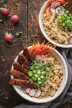 two bowls filled with rice, carrots and radishes on top of a wooden table