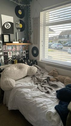 an unmade bed in a dorm room with records on the wall