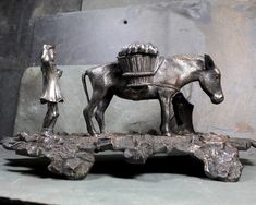 a statue of a horse pulling a cart with a man standing next to it on top of a stone slab