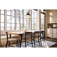 a dining room table and chairs in front of large windows with lots of natural light