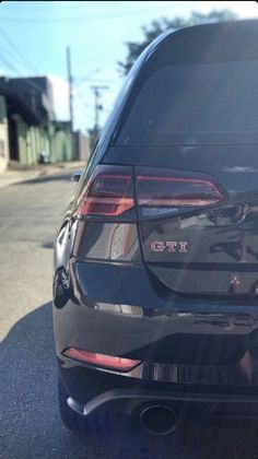 the back end of a black car parked in a parking lot