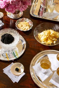 there are plates and bowls on the table with flowers in vases next to them