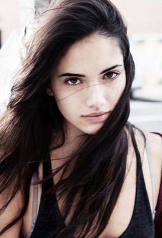 a woman with long dark hair posing for the camera